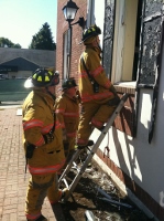 Firefighters climbing into a window